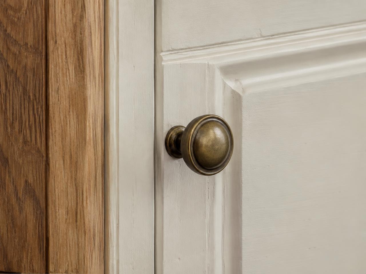 Close detail of oak grain beside a hand-painted door with an aged brass knob